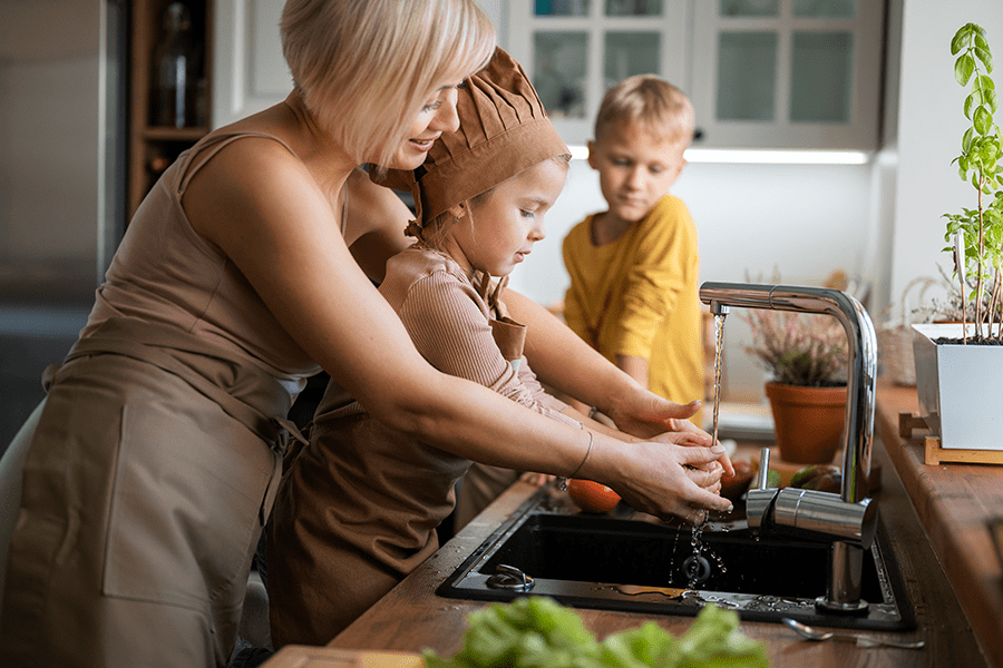 Mutter bringt ihren Kindern das Kochen bei – hygienische und sichere Kücheninstallation mit Sanitärlösungen von dorscht haustechnik.
